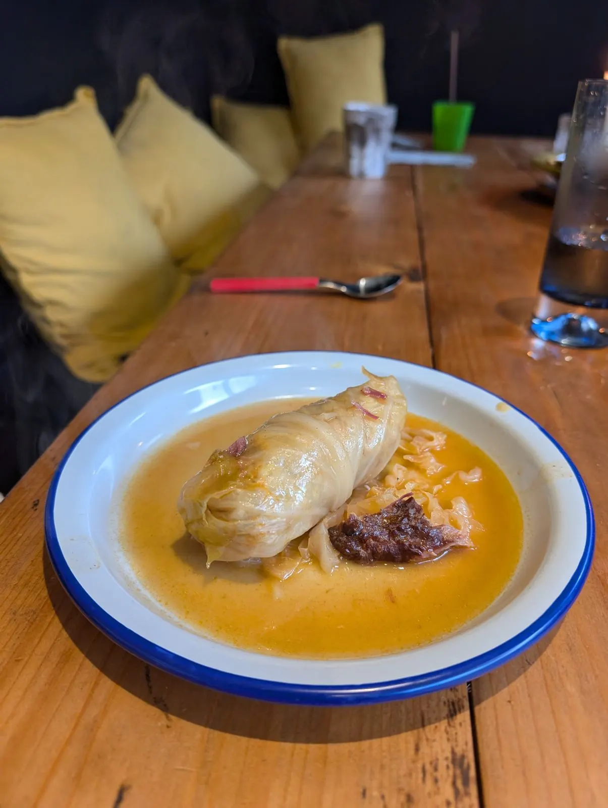 A sarma cabbage roll in paprika broth on an enamel plate with a blue rim